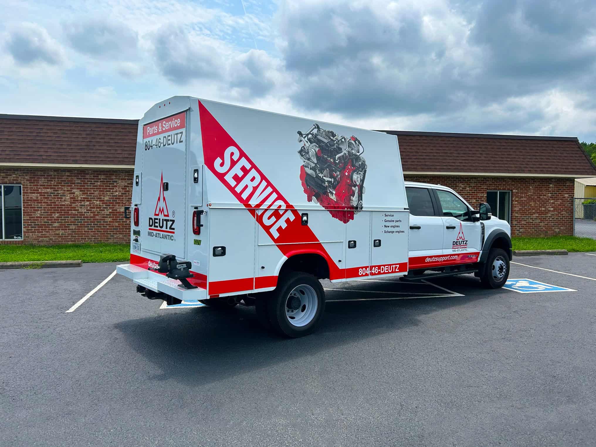 A service truck with Deutz branding and contact information parked in a lot outside a building.