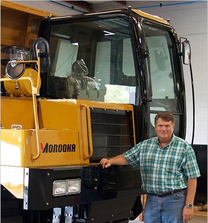 Ken Byrd, President of Morooka USA standing next to a large rubber track carrier that they built